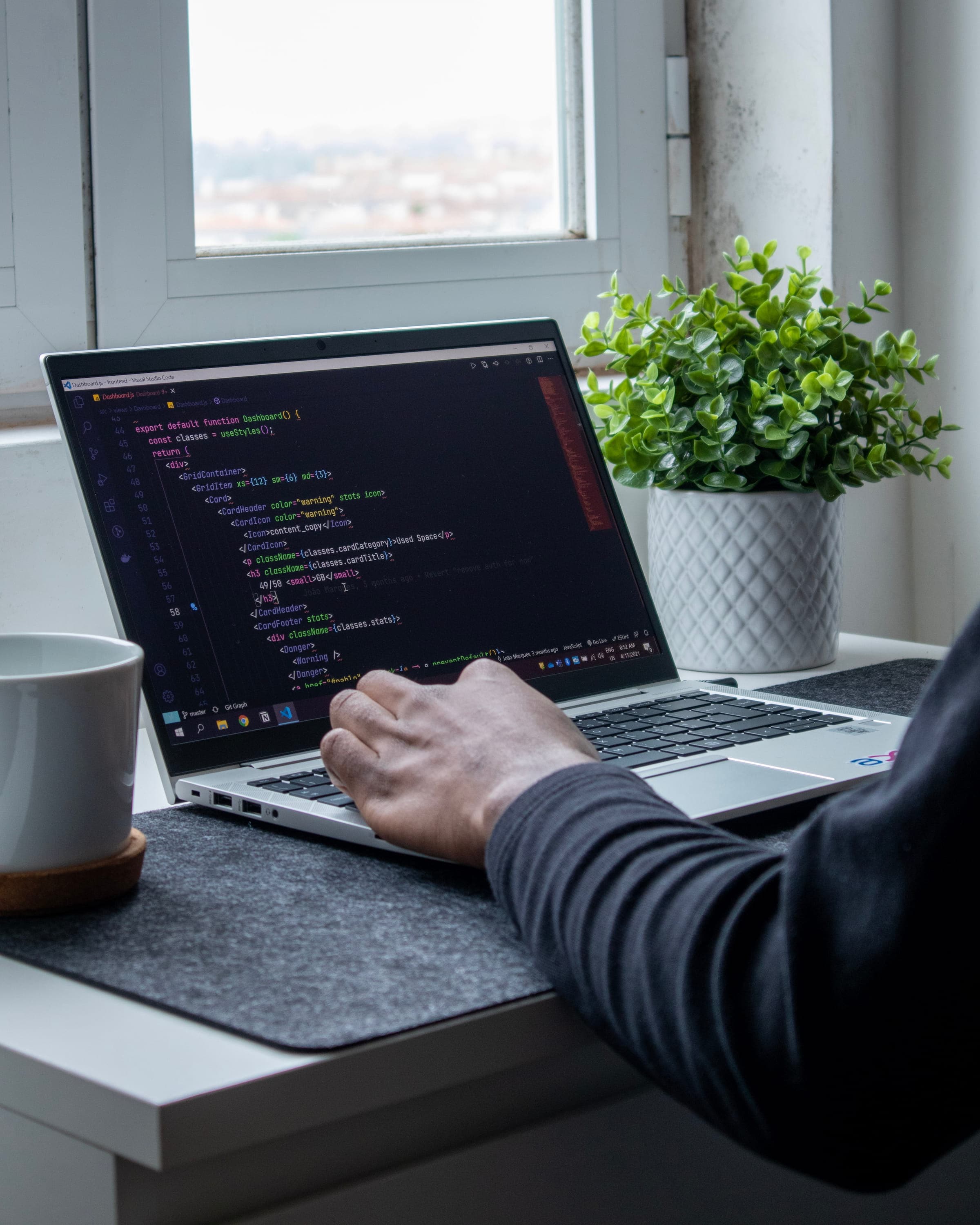 Developer working on a laptop with code visible on the screen